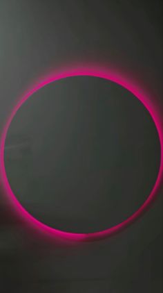 an oval shaped object is lit up in the dark with bright pink light around it