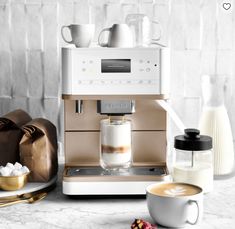 an espresso machine sitting on top of a counter next to cups and saucers