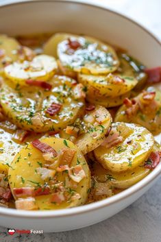 a white bowl filled with potatoes covered in bacon and parsley on top of a table