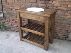 a wooden stand with a sink on top of it next to a brick wall and planter