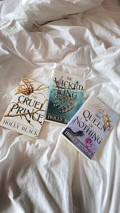 three books laying on top of a bed next to each other in front of a white comforter