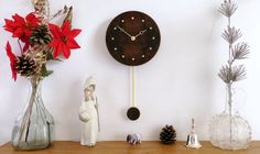 a wooden clock sitting on top of a shelf next to vases and pine cones