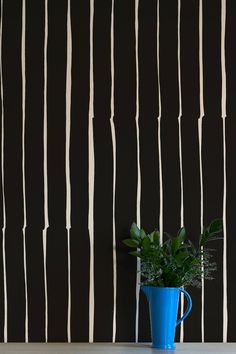 a blue vase sitting on top of a table next to a black and white wall