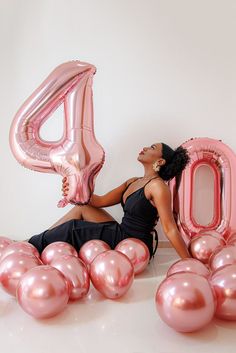 a woman sitting on the floor with balloons in front of her and number forty balloon