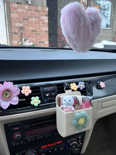 a car dashboard with a stuffed animal hanging from it's center console and some flowers on the dash board