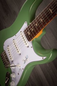 a green and white guitar sitting on top of a wooden floor