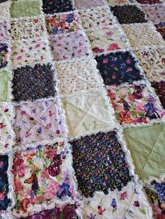 an old quilt is laying on top of a tablecloth that has flowers all over it