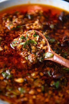 a wooden spoon filled with soup and vegetables