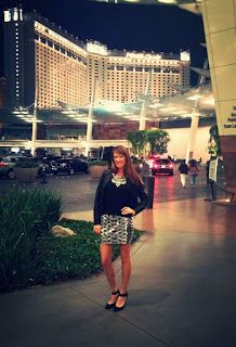 a woman is standing in front of the las vegas hotel and casino towers at night