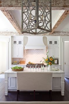 a kitchen with white cabinets and an island in front of the stove top is surrounded by sunflowers