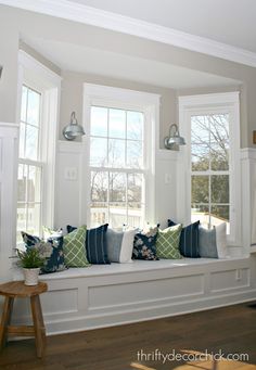 a window seat with pillows and bunting on the windowsill in a white room