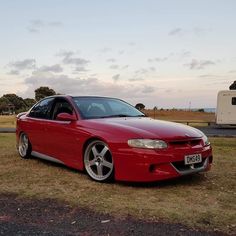 a red car is parked in the grass