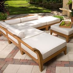 a couch and ottoman sitting on top of a stone patio floor next to a potted plant