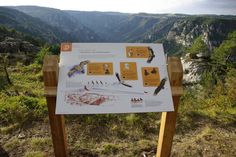 a sign on the side of a mountain with birds perched on it's wings