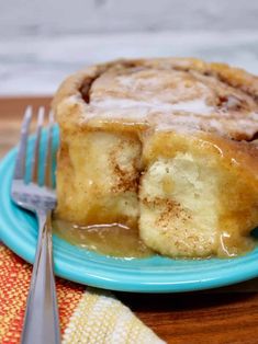 a piece of cinnamon roll sitting on top of a blue plate next to a fork