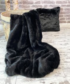 a large black furry chair sitting on top of a white floor next to a brick wall