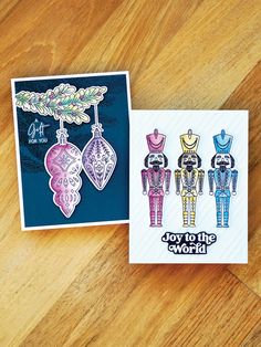 two greeting cards with the words joy to the world written on them and an ornament hanging from a tree