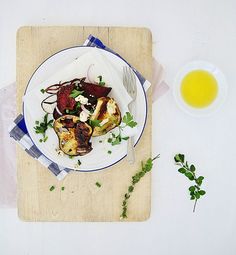 a white plate topped with food on top of a wooden cutting board next to a cup of tea