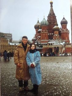 a man and woman standing in front of a building with domes on the top of it