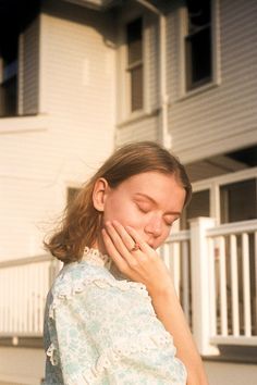 a woman is standing outside with her hands on her face and looking down at the ground