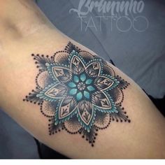 a tattoo on the arm of a woman with an intricate flower design in blue and green