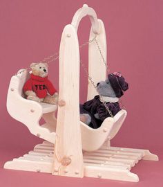 two teddy bears sitting in a miniature sleigh with clothes on it's back