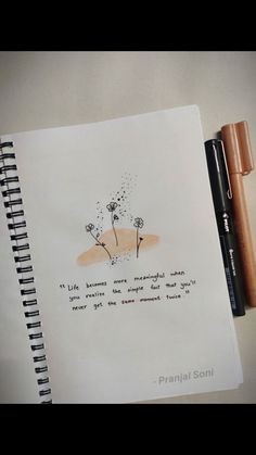 a notepad with a drawing of two dandelions on it next to a pen