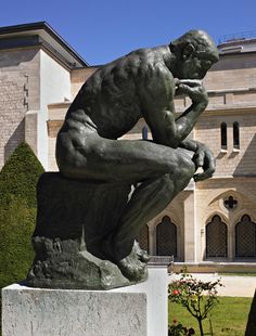 a statue of a man sitting on top of a cement block in front of a building