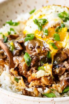 a white bowl filled with rice and meat covered in an egg on top of it