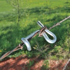 a close up of a barbed wire with grass in the background