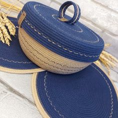 two blue baskets sitting on top of each other next to some wheat stalks in front of a brick wall