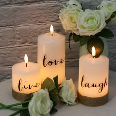 three lit candles with the words love, live laugh and roses in front of them