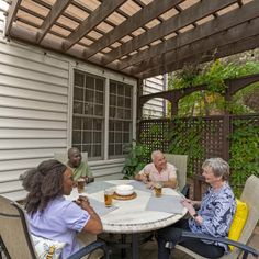 four people sitting around a table with cake and beer in front of them on a patio