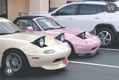 two pink and white sports cars parked next to each other in a parking lot with hearts painted on the hoods