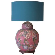 a pink and blue vase with a green lamp on the bottom is sitting in front of a white background