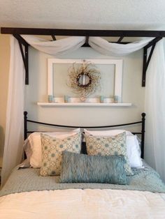 a bed with white sheets and pillows under a canopy over it's headboard