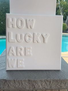 a white sign that says how lucky are we on the side of a swimming pool