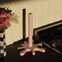 a vase with flowers in it sitting on a counter next to a stove top burner