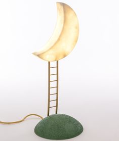 a lamp with a ladder to the moon on it and a green rock under it