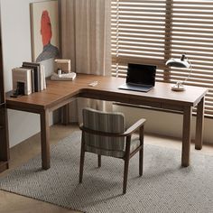 a computer desk with a laptop on top of it next to a chair and bookshelf