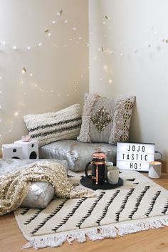 a living room filled with lots of pillows and blankets on top of a wooden floor