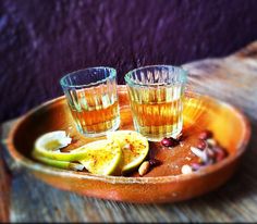 two glasses filled with liquid sitting on top of a wooden tray