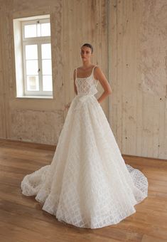 a woman in a white wedding dress standing on a wooden floor next to a window