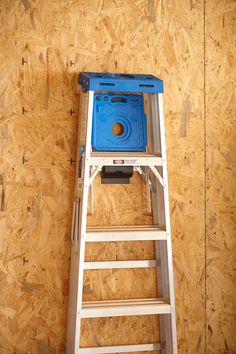 a blue stool sitting on top of a wooden step ladder