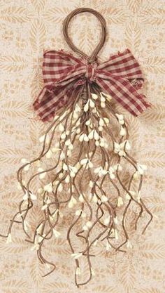 a red and white bow is hanging from a metal hook on a beige fabric wall