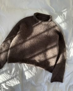 a brown sweater laying on top of a white sheet