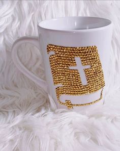 a white coffee mug with gold sequins on the side and a letter f in the middle