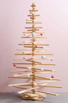 a wooden christmas tree with ornaments on it's branches and balls hanging from the top