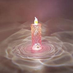 a pink candle floating in water with ripples