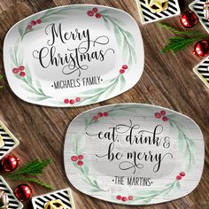 two oval plates with merry christmas sayings on them and ornaments around the edges, sitting on a wooden surface